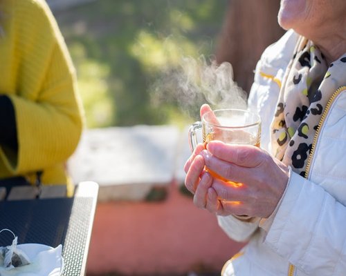 Person enjoying morning sunshine with a cup of tea